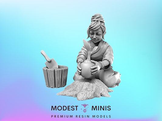 A 3D model of a woman sitting on a rock, holding a small object in her hands, with a wooden bucket next to her.